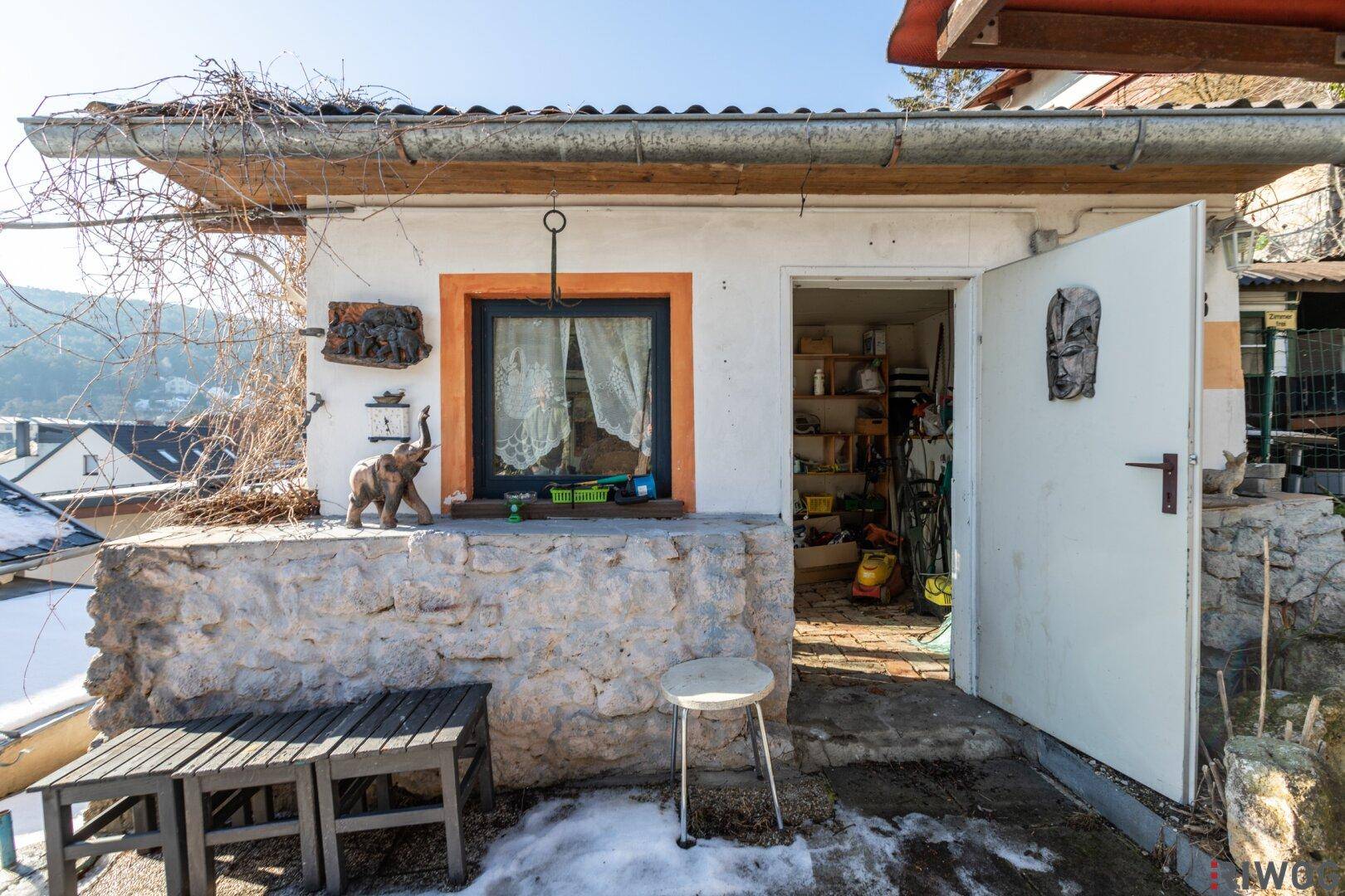 Kleines Gartenhaus mit offener Tür, das als Abstellraum für Werkzeuge und Geräte dient.