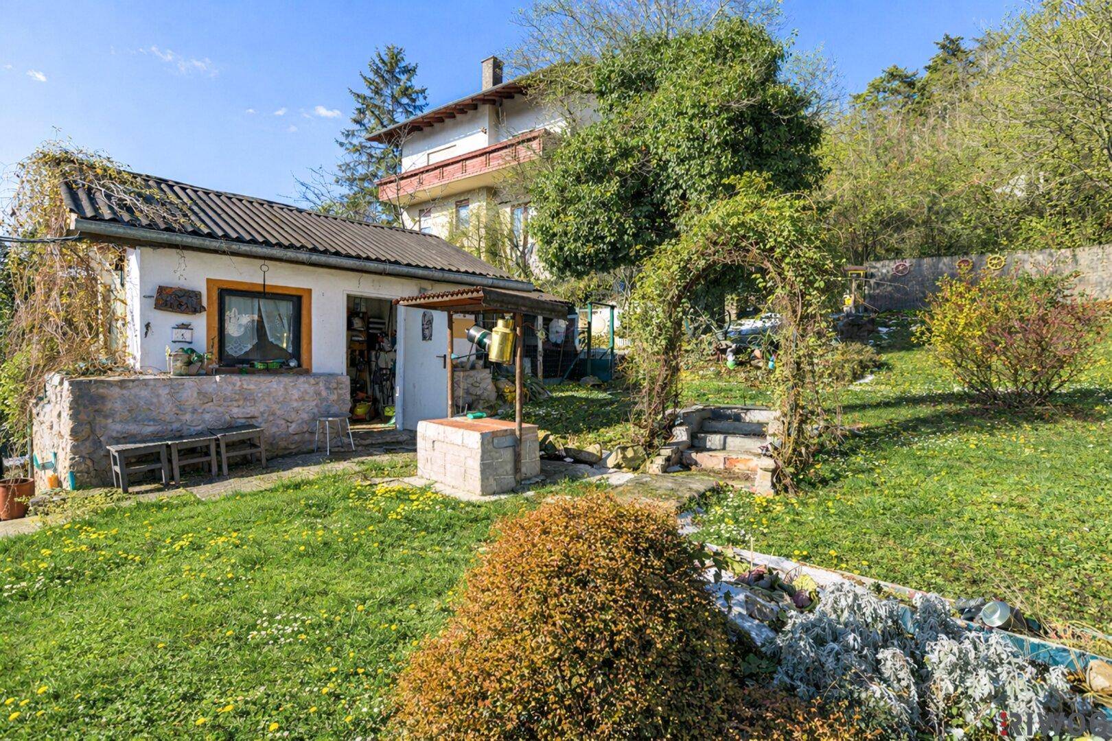 Großer Garten mit Gartenhaus, einem dekorativen Bogen und viel Grünfläche.