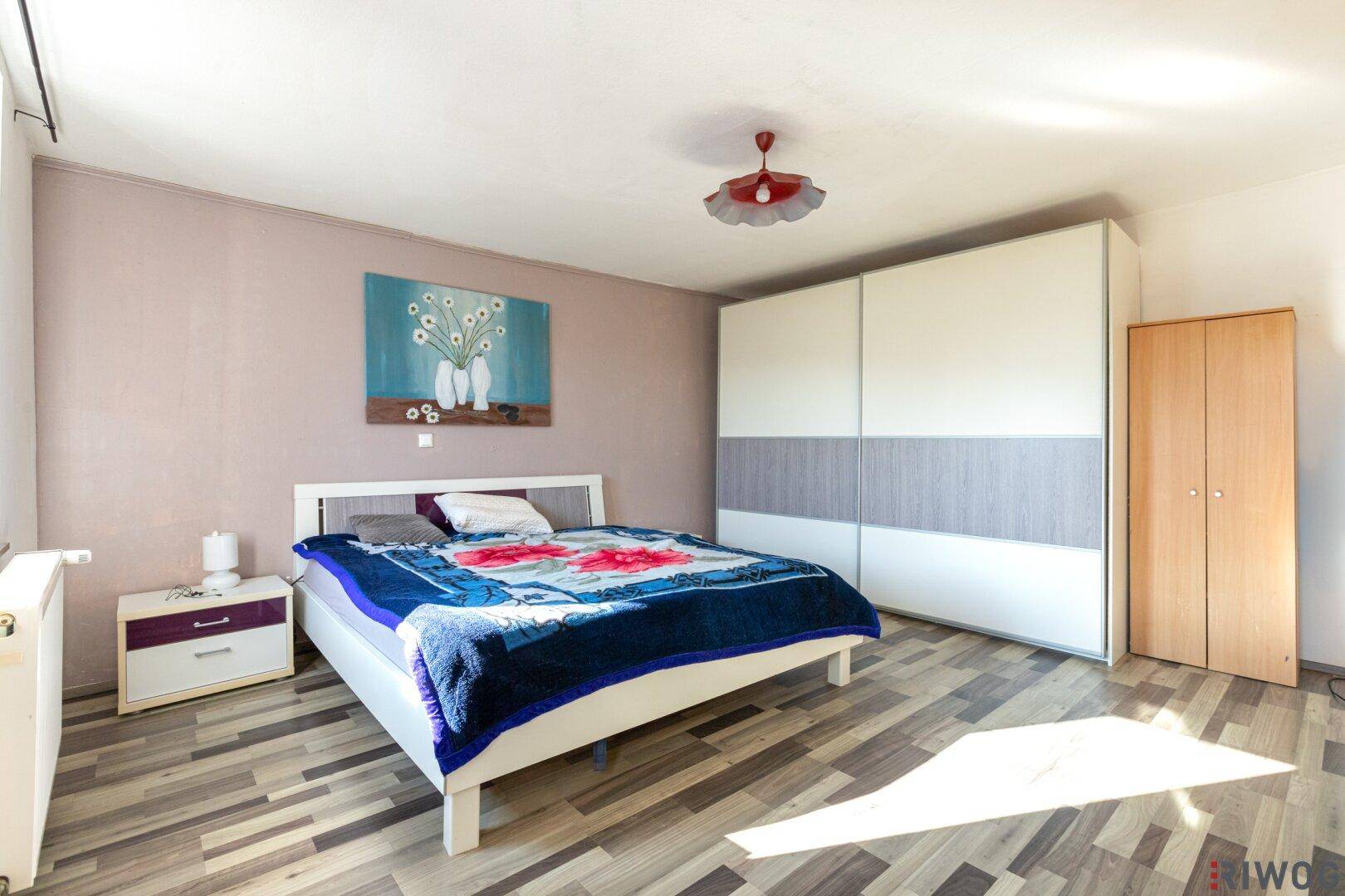 Helles Schlafzimmer mit großem Kleiderschrank, Doppelbett und Laminatboden.