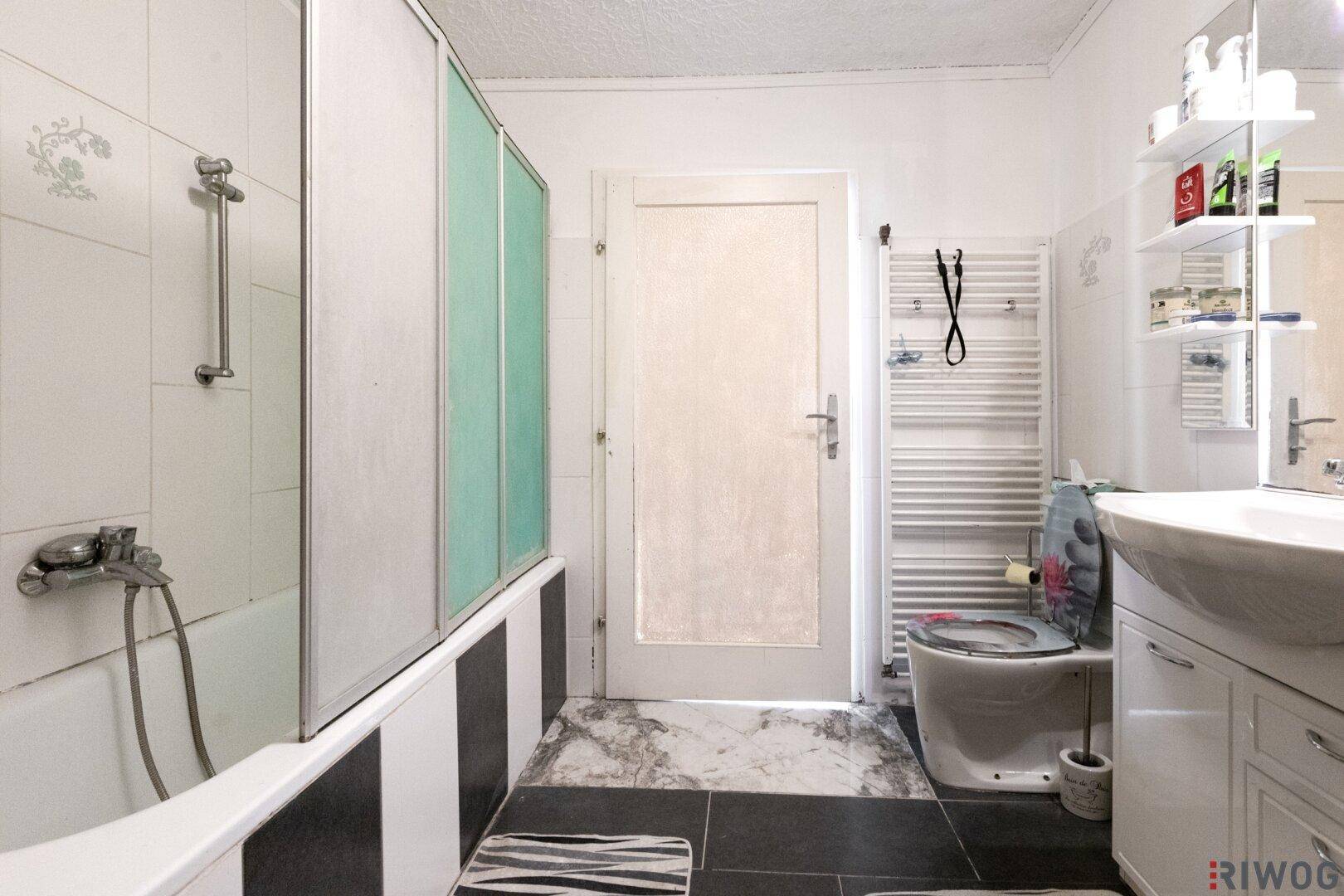 Badezimmer mit Badewanne, Duschabtrennung, WC und beheiztem Handtuchhalter.