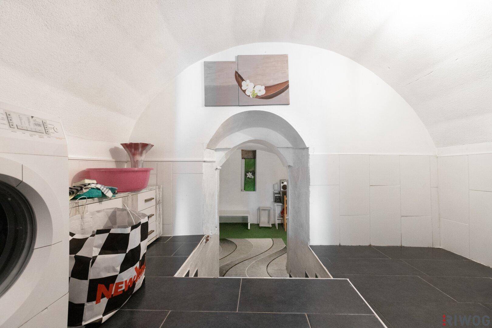 Geräumiger Kellerraum mit gewölbter Decke und Durchgang zu einem weiteren Bereich.
