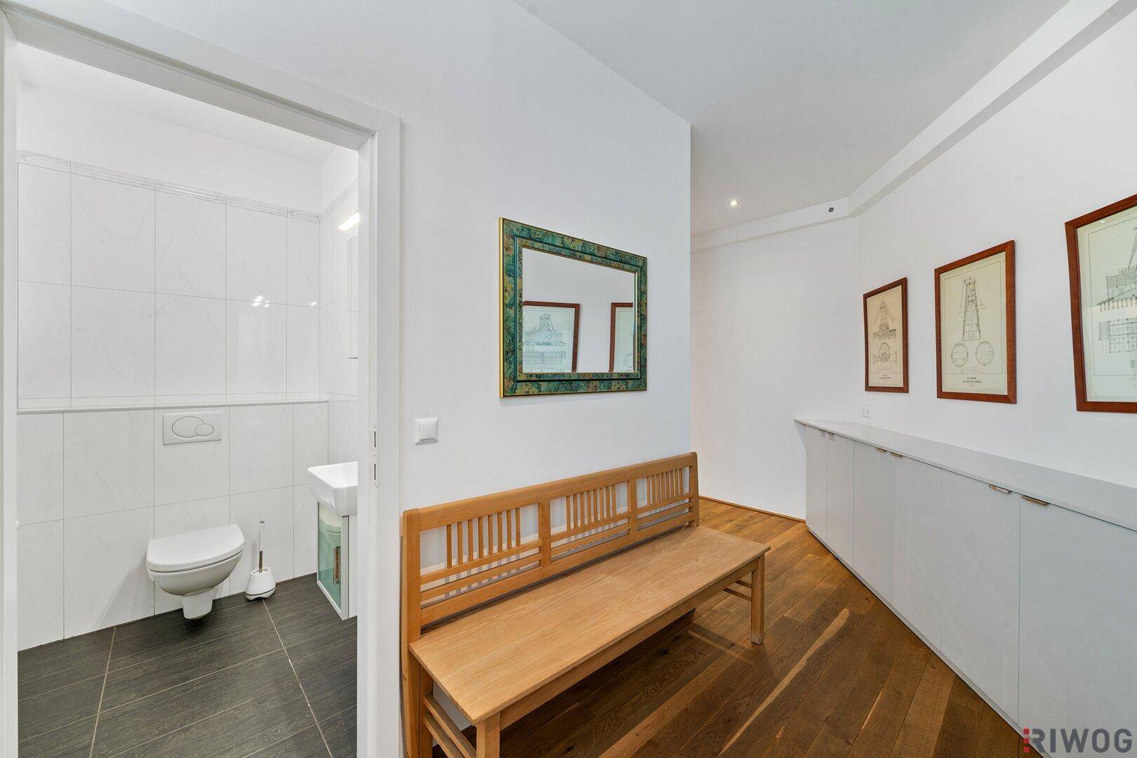 Heller Flur mit Holzboden und Zugang zu einer separaten Gästetoilette.