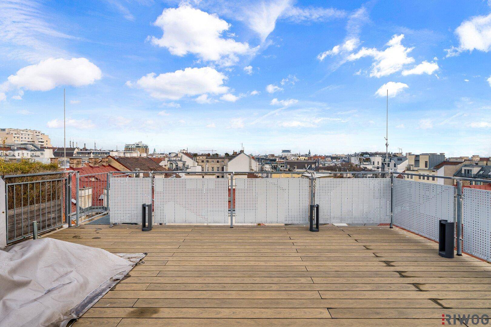 Weitläufige Dachterrasse mit Holzboden und Panoramablick über die Stadt.