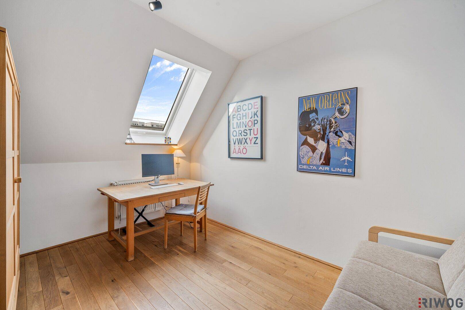 Helles Arbeitszimmer im Dachgeschoss mit Schreibtisch, Holzboden und Dachfenster.