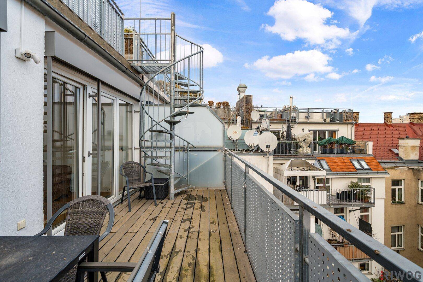 Balkon mit Stadtblick, Außentreppe zur Dachterrasse und Sitzgelegenheiten.