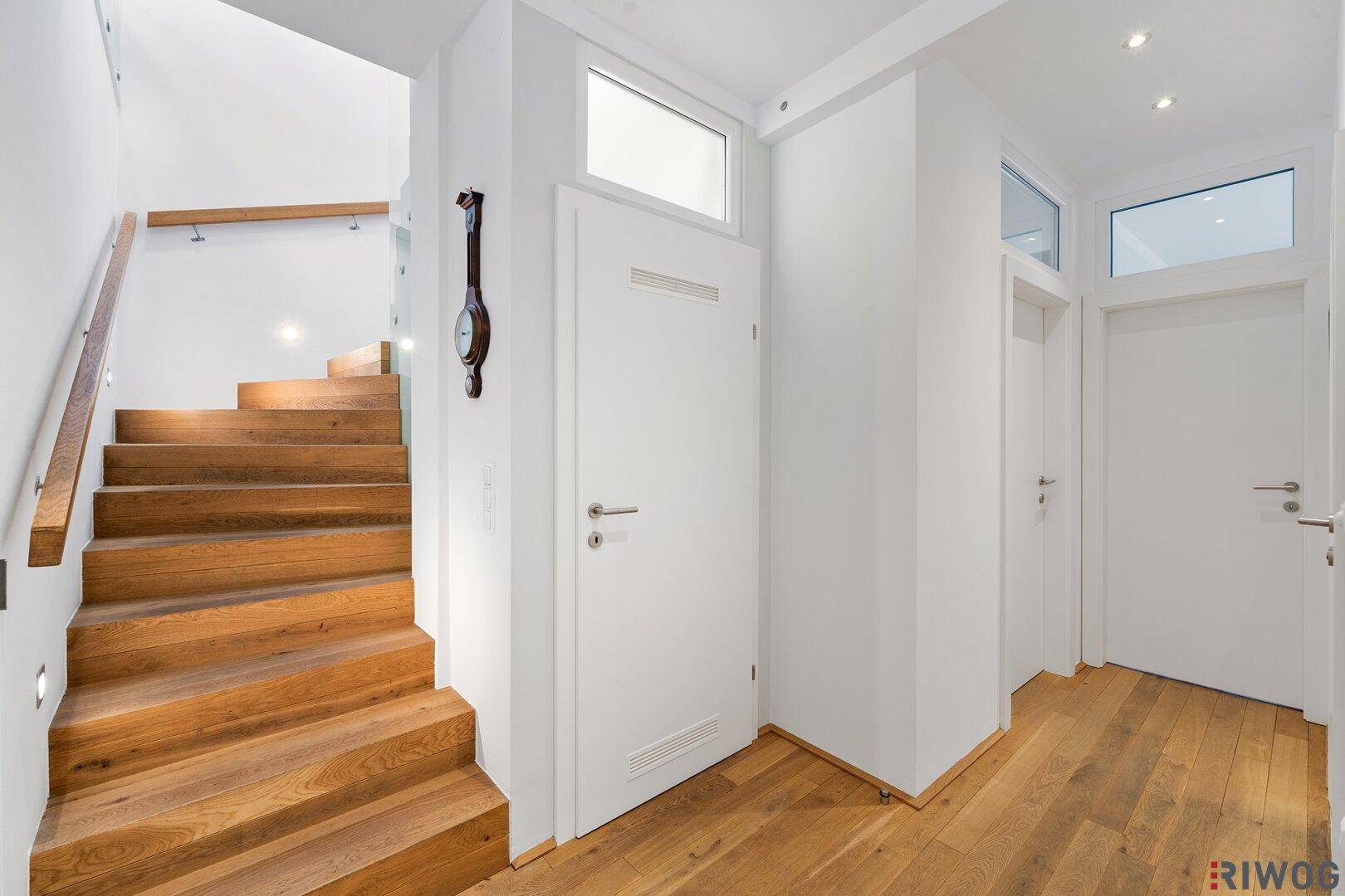 Heller Flur mit Holztreppe und Holzboden, der zu den oberen Etagen führt.