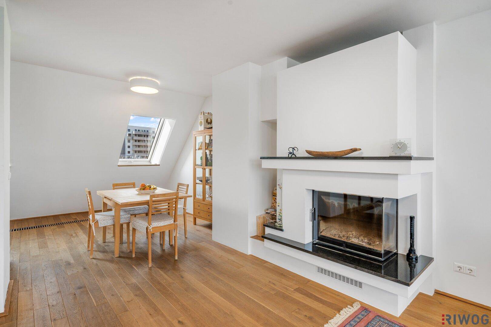 Heller Essbereich mit Holzboden und modernem Kamin, der eine gemütliche Atmosphäre schafft.