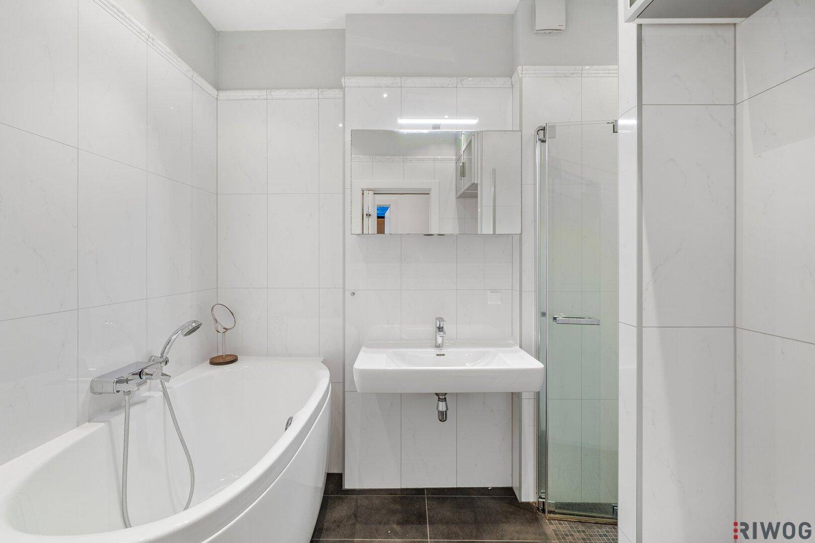 Modernes Badezimmer mit Badewanne, Dusche, Einzelwaschbecken und weißen Fliesen.