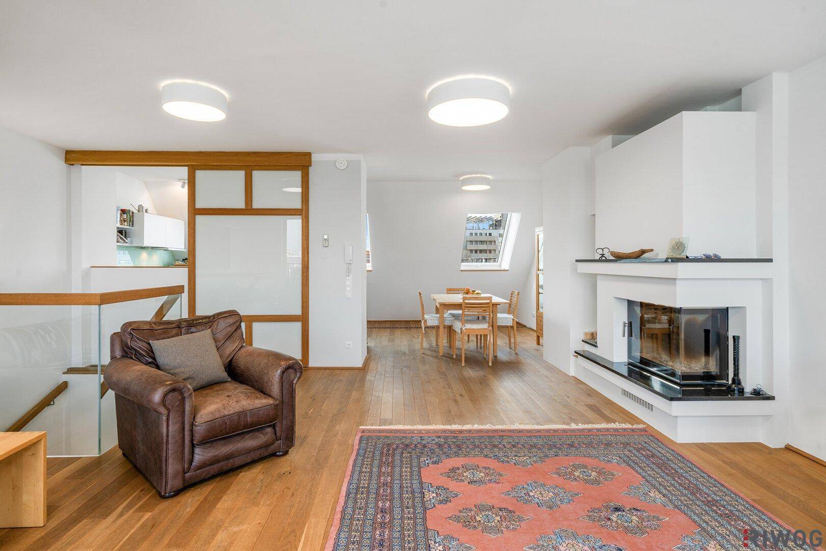 Offener Wohnbereich mit Kamin, Holzboden und Blick auf den Essbereich und die Küche.