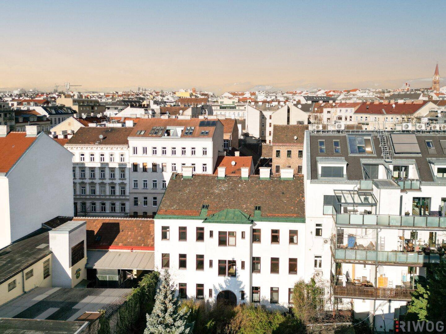 Panoramablick über die Dächer der Stadt mit verschiedenen Gebäuden und einem Kirchturm in der Ferne.