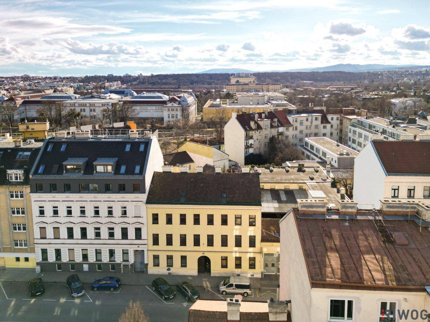 Panoramablick über eine Stadt mit verschiedenen Gebäuden und einer Bergkette am Horizont.