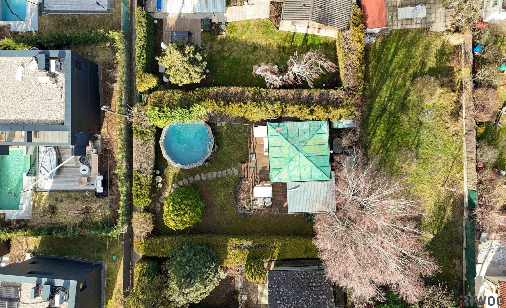 Vogelperspektive des Anwesens mit Garten, Pool und dem grünen Dach des Hauses.