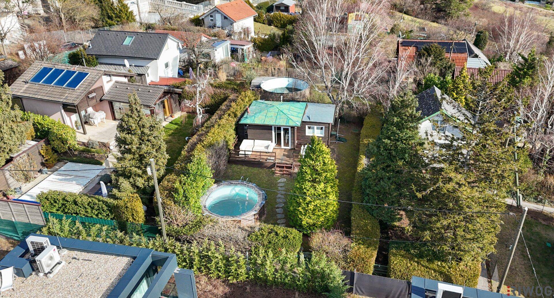 Übersicht des Anwesens mit Garten, Pool und den angrenzenden Häusern in der Nachbarschaft.