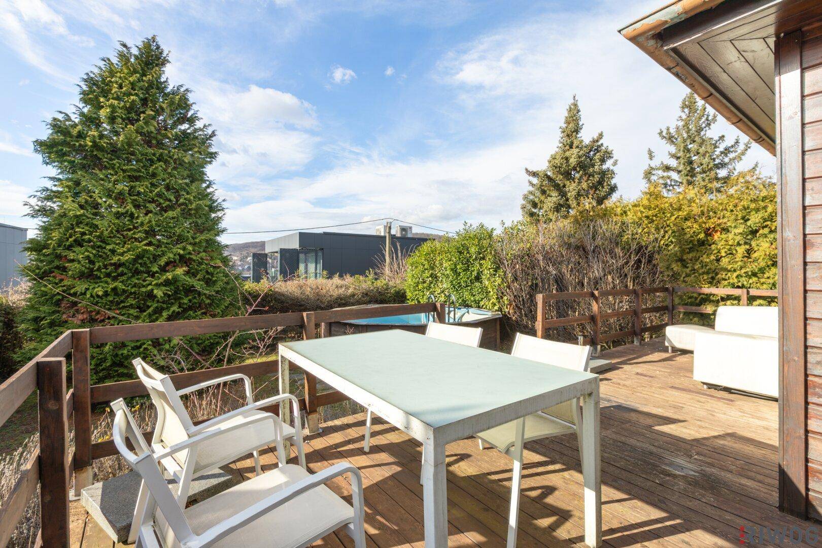 Holzterrasse mit modernem Esstisch und Stühlen, ideal für Mahlzeiten im Freien.