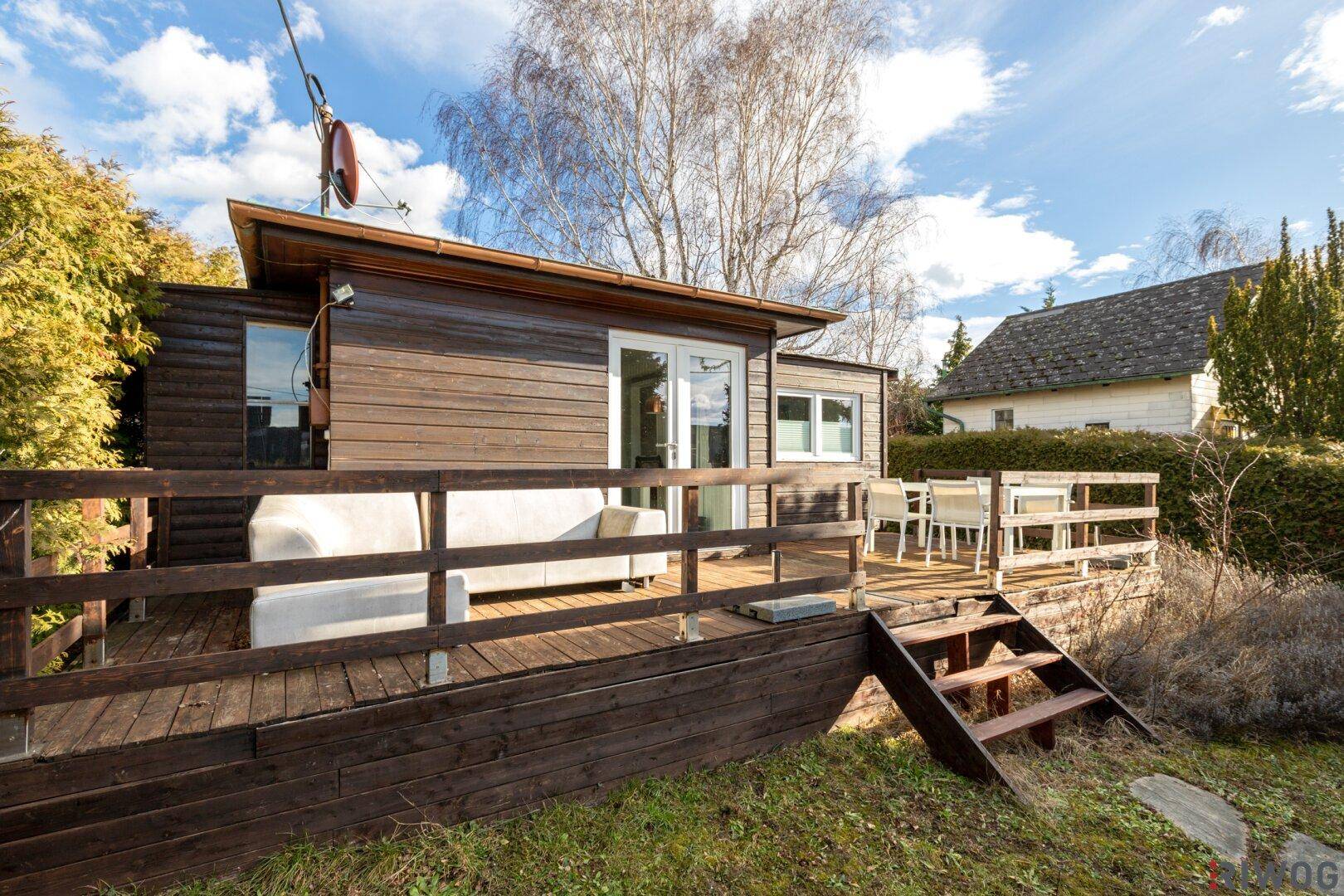 Gemütliche Holzterrasse am Haus mit Sitzgelegenheiten und Blick ins Grüne.