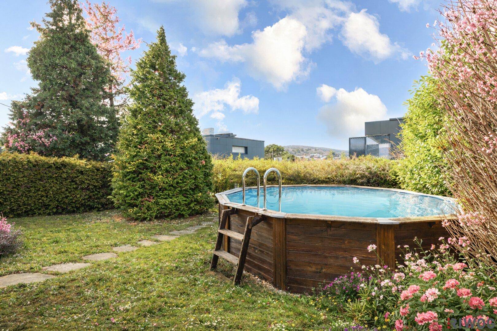 Runder Aufstellpool im grünen Garten, umgeben von blühenden Pflanzen und Rasen.
