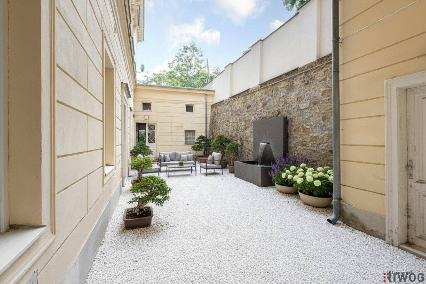 Heller Innenhof mit moderner Sitzgruppe, Steinmauer und dekorativem Wasserbecken.