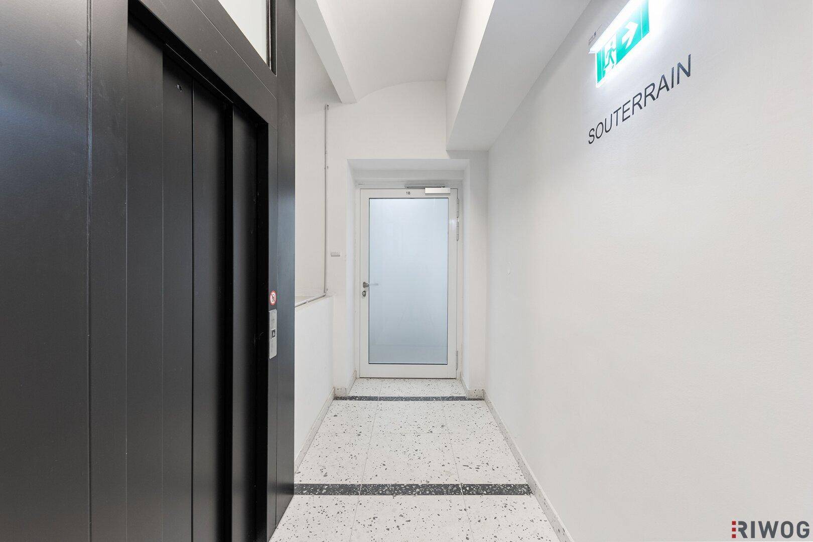 Heller Flur mit Aufzug und Zugang zum Souterrain, ausgestattet mit Terrazzoboden.