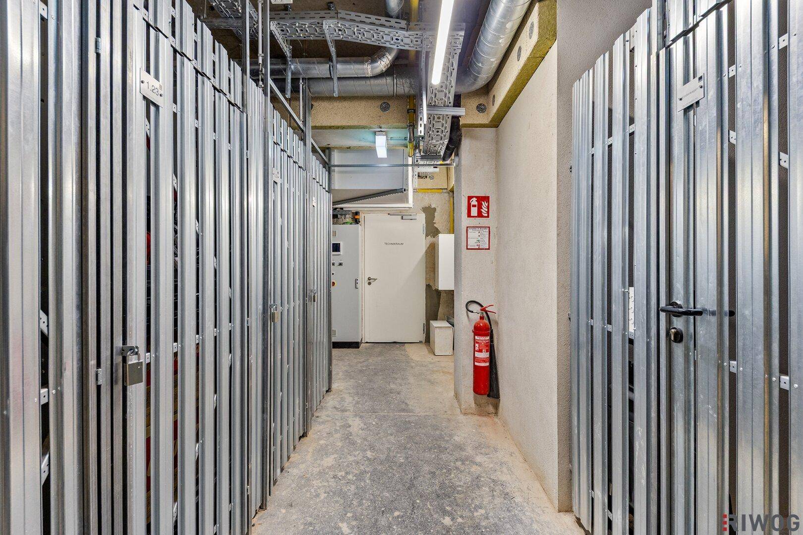 Kellerabteil mit individuellen Lagereinheiten und sichtbaren Installationen an der Decke.