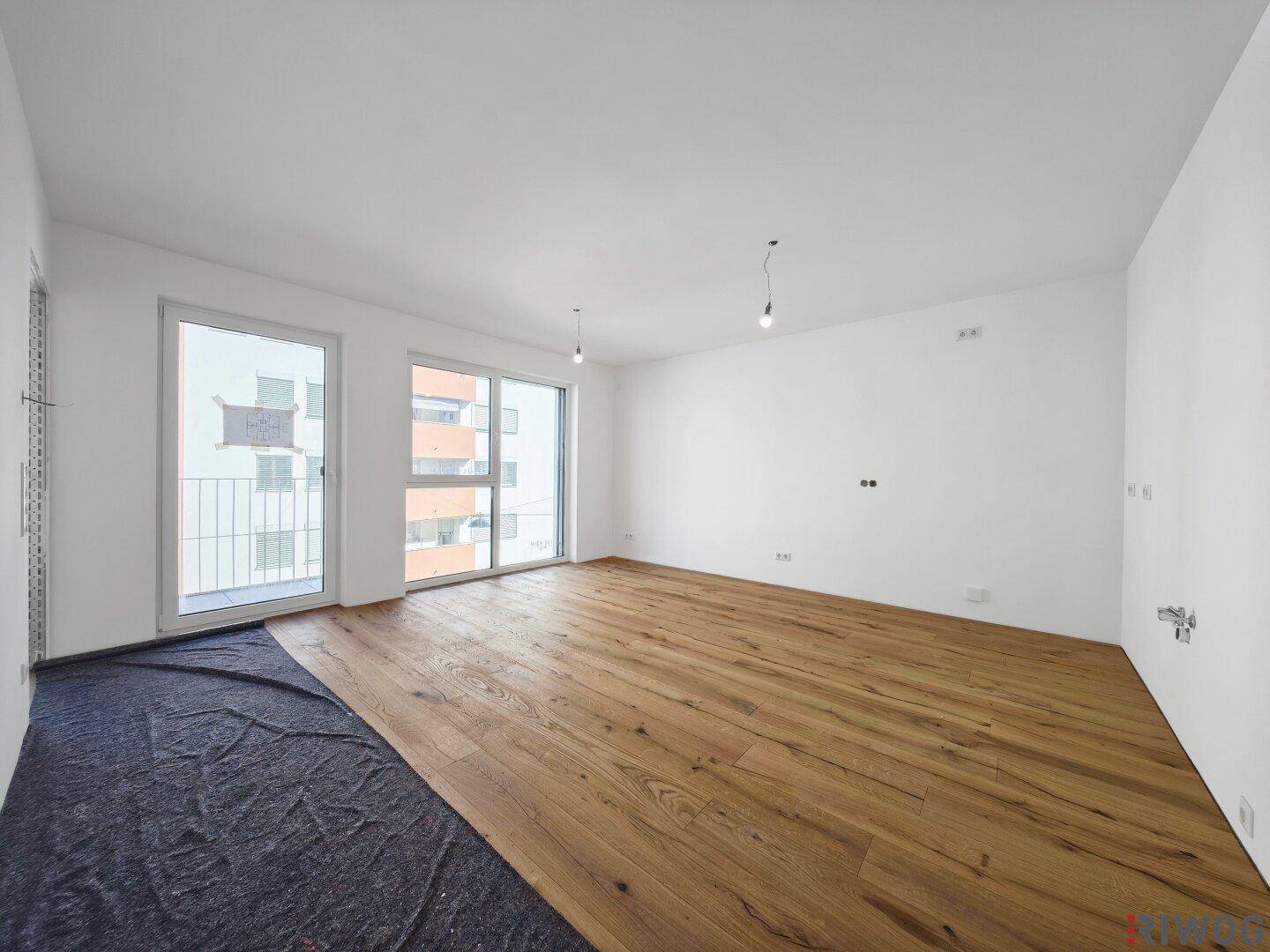 Geräumiger, heller Wohnbereich mit neuem Holzfußboden und großen Fenstern zum Außenbereich.
