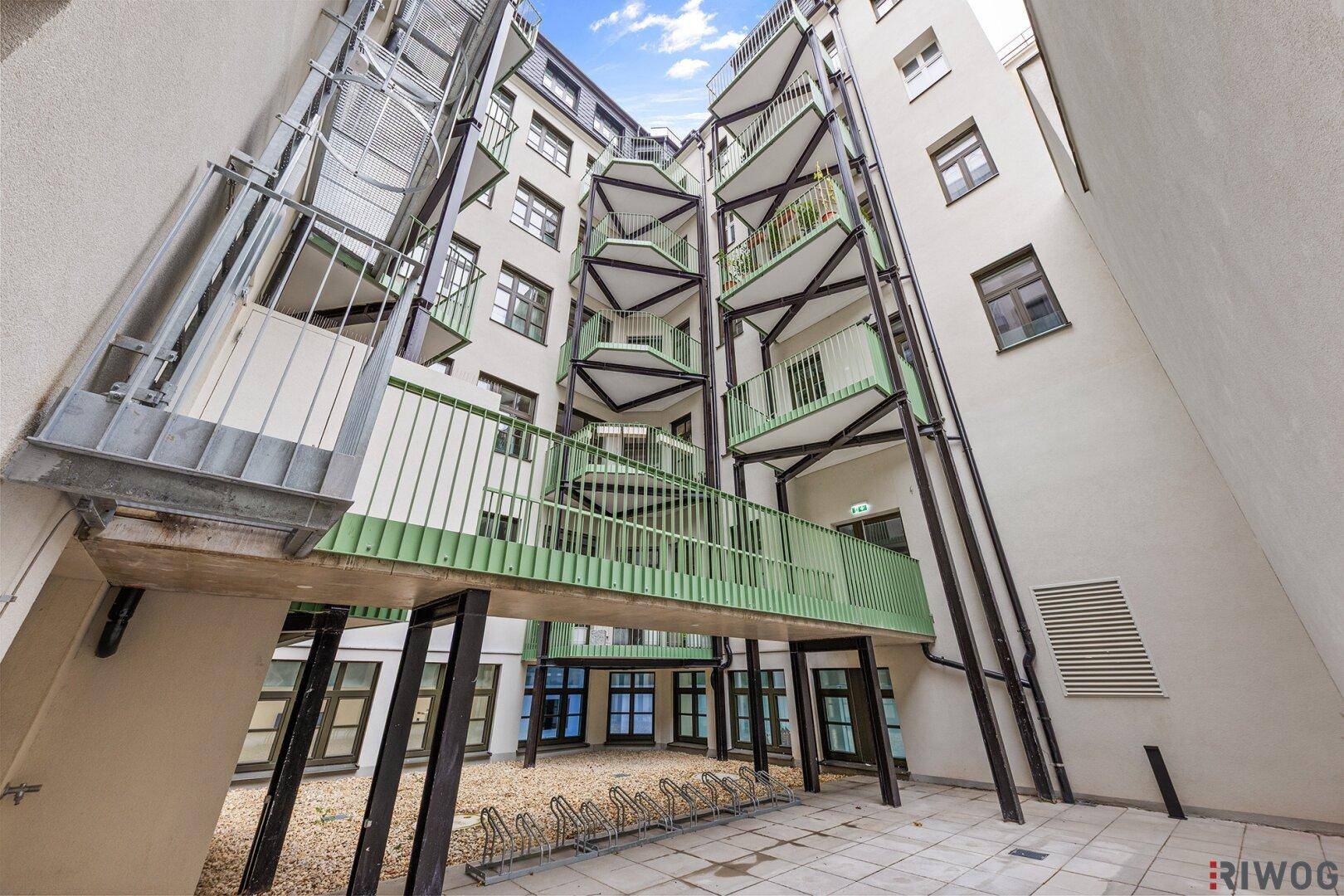 Moderner Innenhof mit gestaffelten Balkonen, Fahrradständern und offener Architektur.