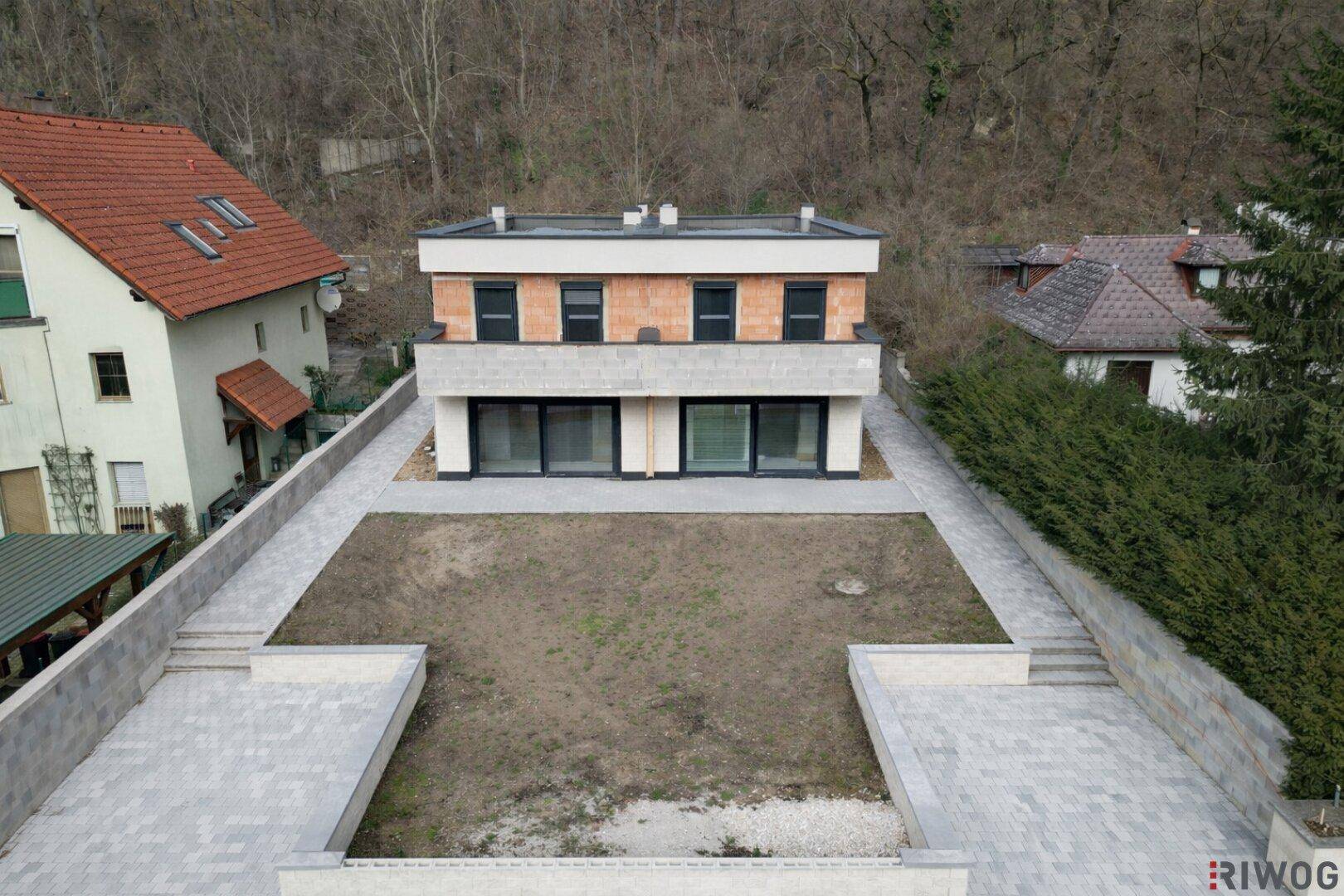 Neubau-Doppelhaushälfte mit vorbereitetem Gartenbereich und moderner Architektur.