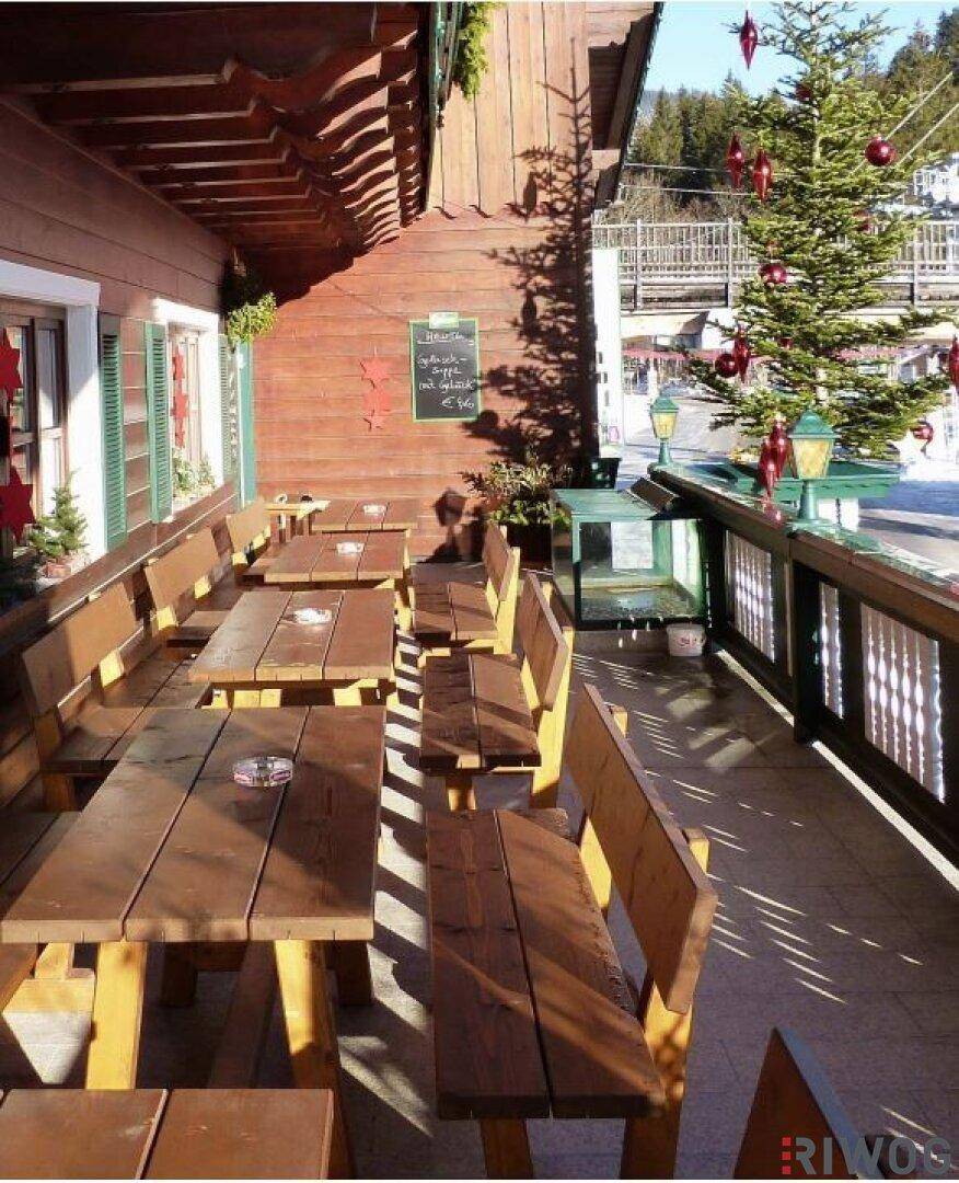 Gemütliche Außenterrasse mit Holzbänken und Tischen, festlich dekoriert für die Weihnachtszeit.