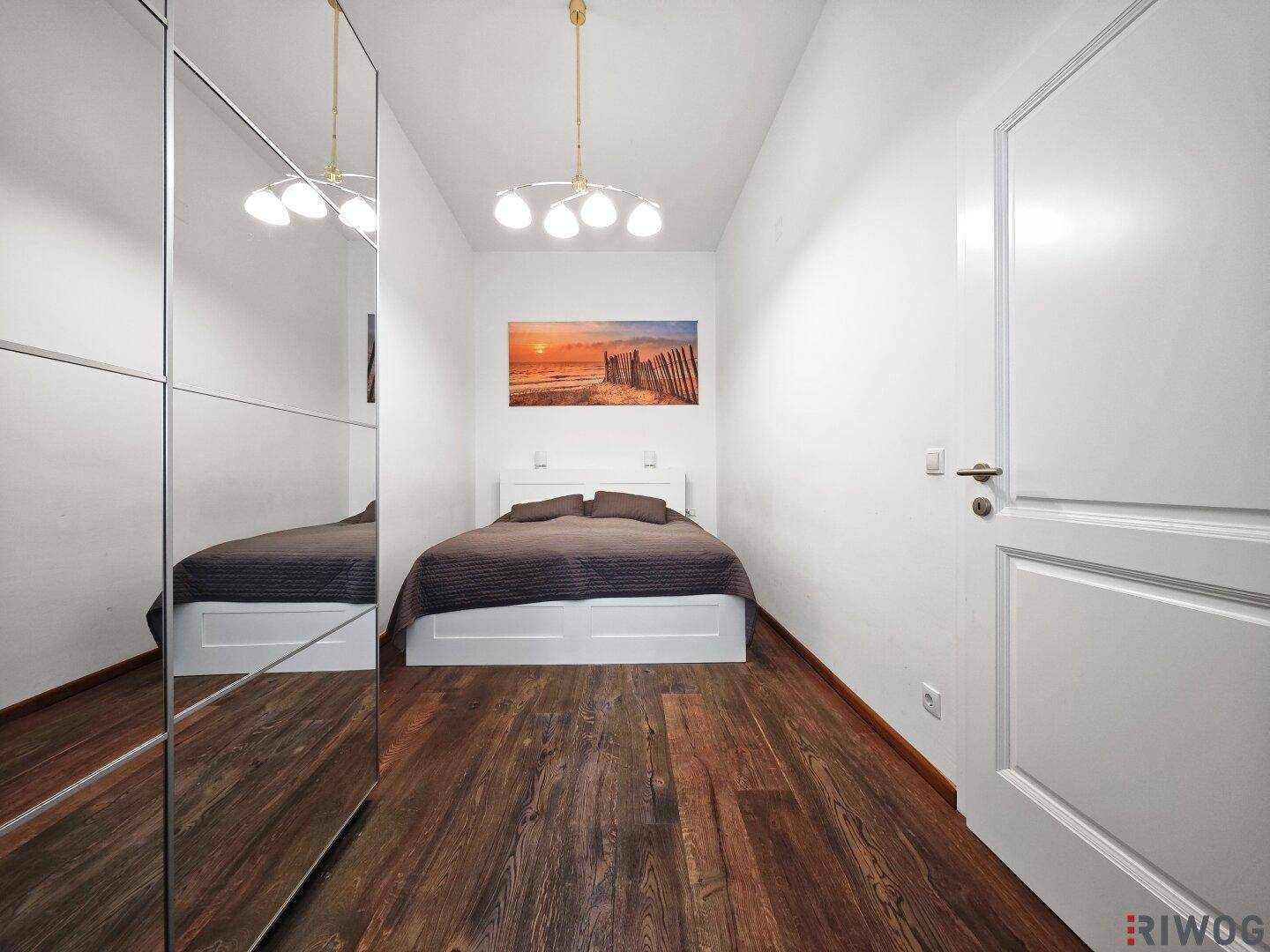 Gemütliches Schlafzimmer mit Holzboden, Spiegelschrank und hellem Ambiente.