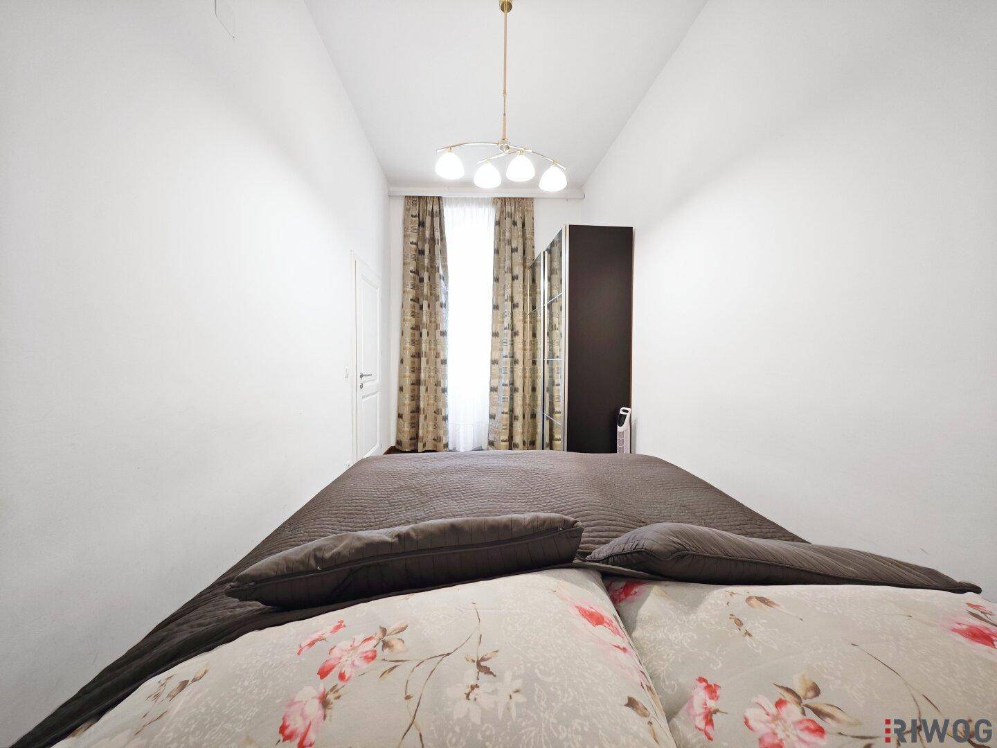 Schlafzimmer mit Holzboden, Fenster und Vorhängen, bietet eine ruhige Atmosphäre.