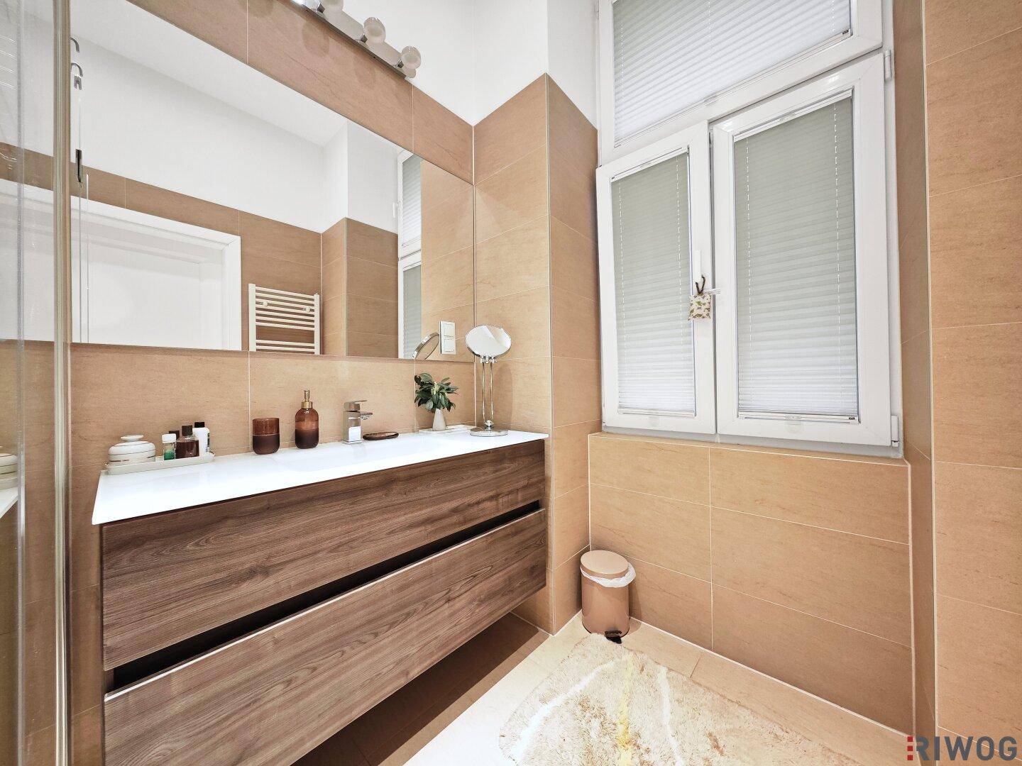Helles Badezimmer mit Fenster, großem Spiegel und modernem Holzwaschtisch.