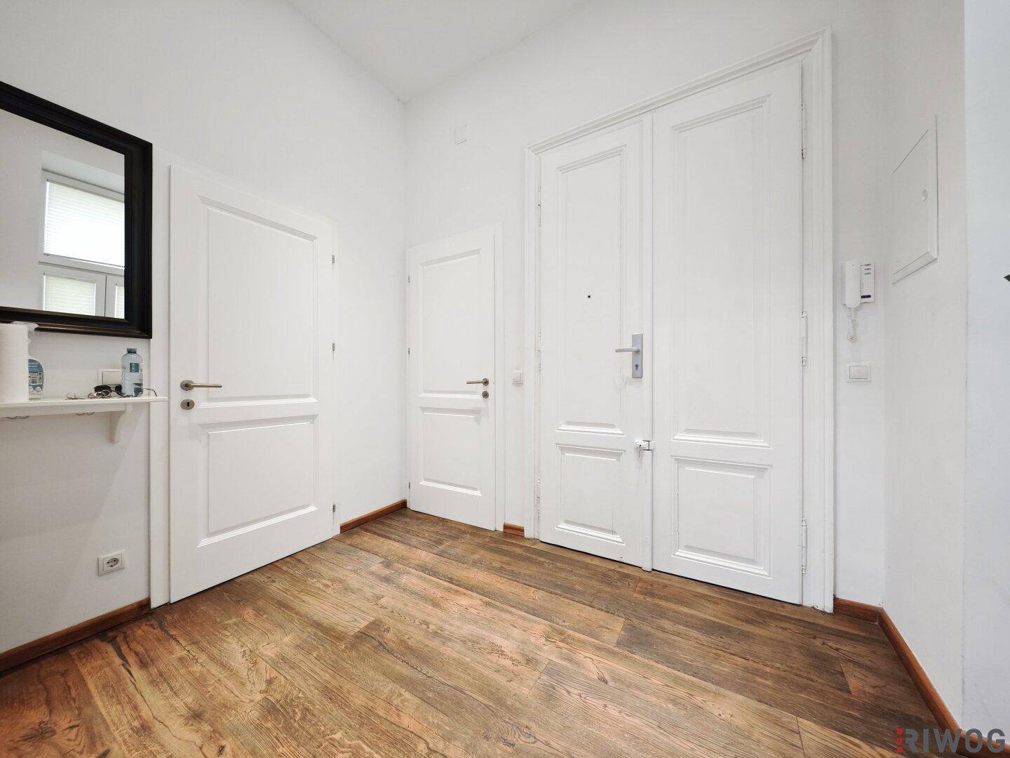 Geräumiger Flur mit Holzboden und mehreren weißen Türen, bietet viel Platz.
