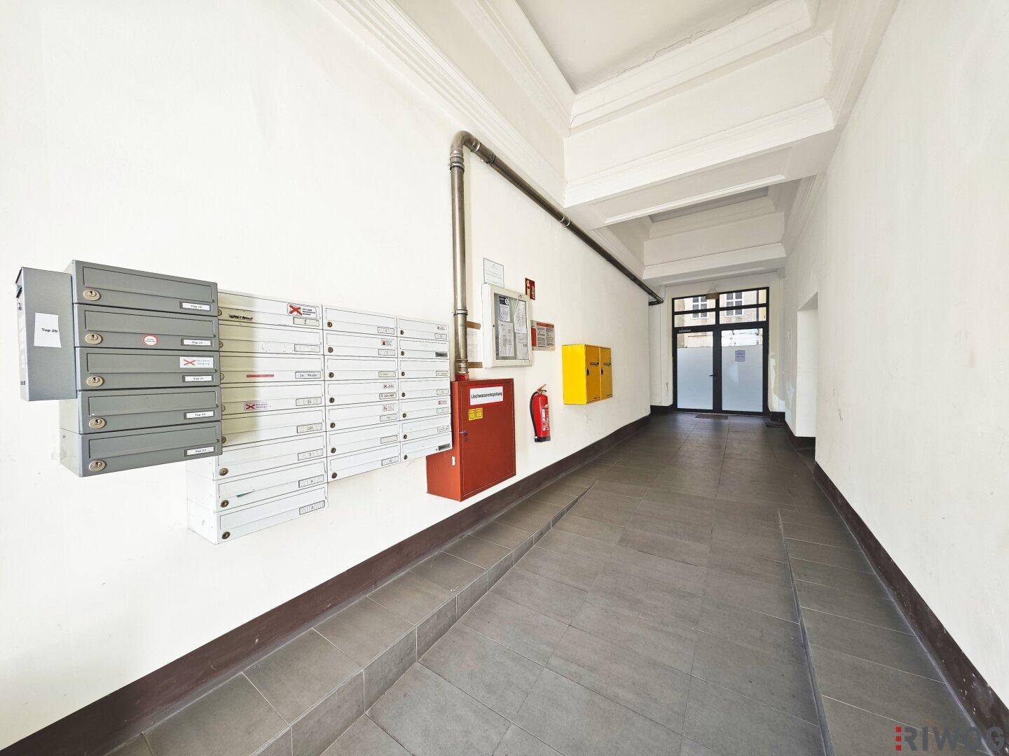 Heller Eingangsbereich mit Briefkästen, Rampe und Zugang zum Gebäude.