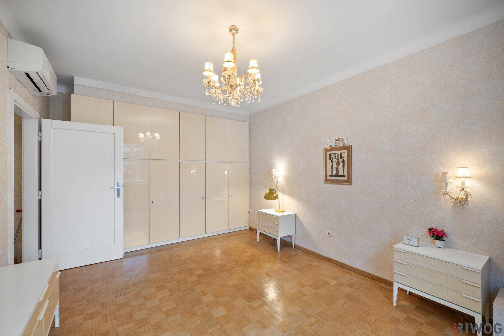 Schlafzimmer mit Einbauschränken, Parkettboden und Kronleuchter.