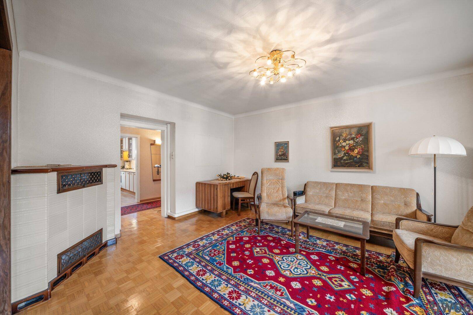 Wohnzimmer mit traditionellem Kachelofen, Parkettboden und vintage Einrichtung.