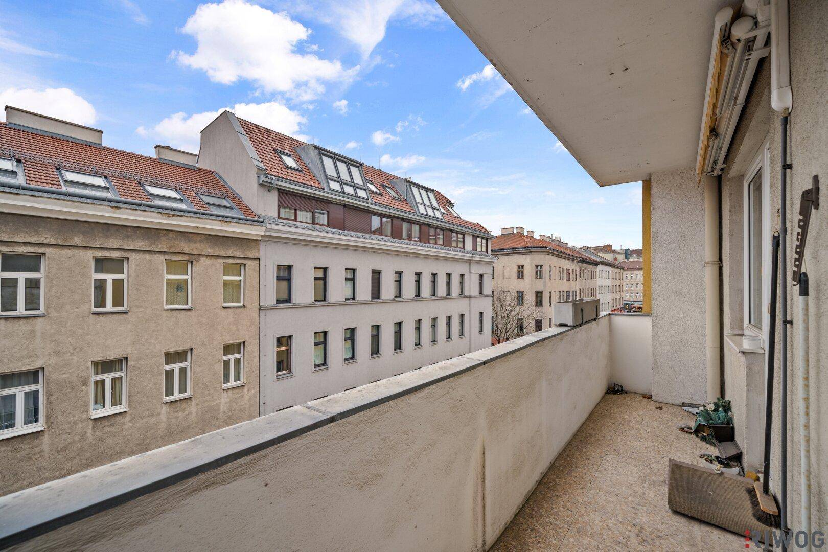 Schmaler Balkon mit Ausblick auf die Dächer der Stadt und angrenzende Gebäude.