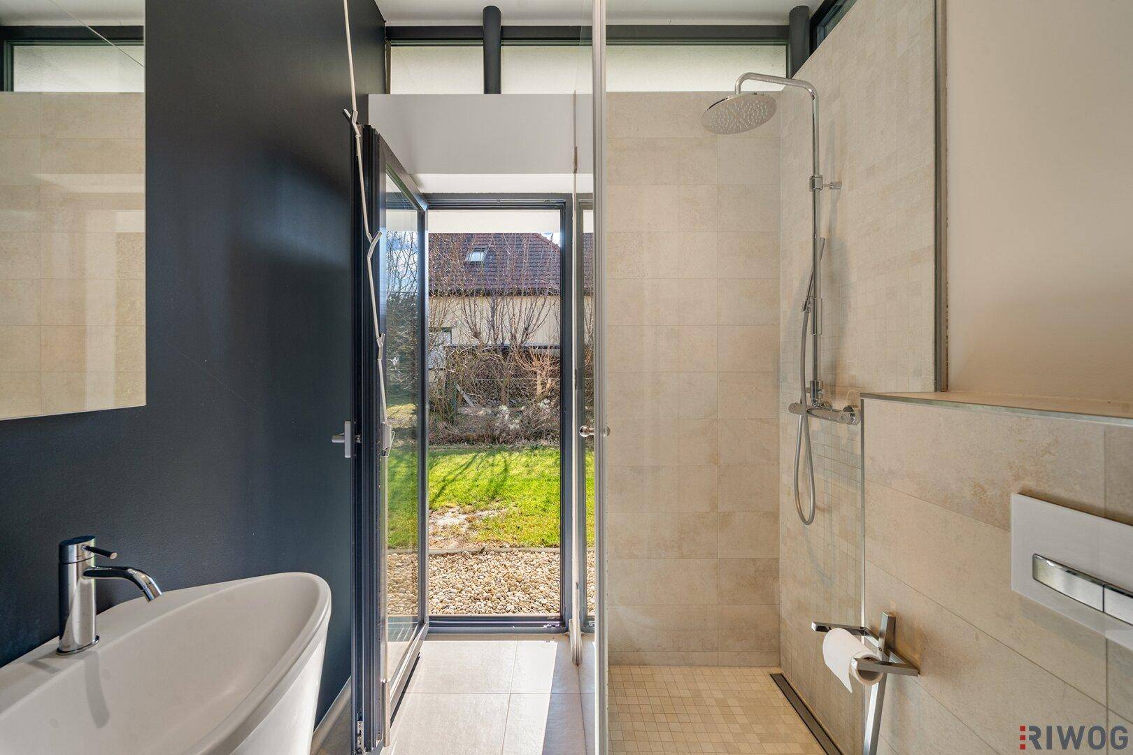 Modernes Badezimmer mit ebenerdiger Dusche, Regendusche und Zugang zum Garten.