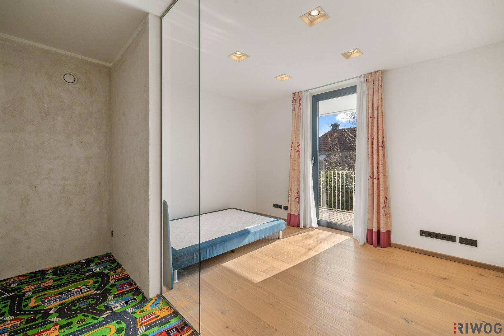 Helles Kinderzimmer mit Holzboden, französischem Balkon und Blick ins Grüne.