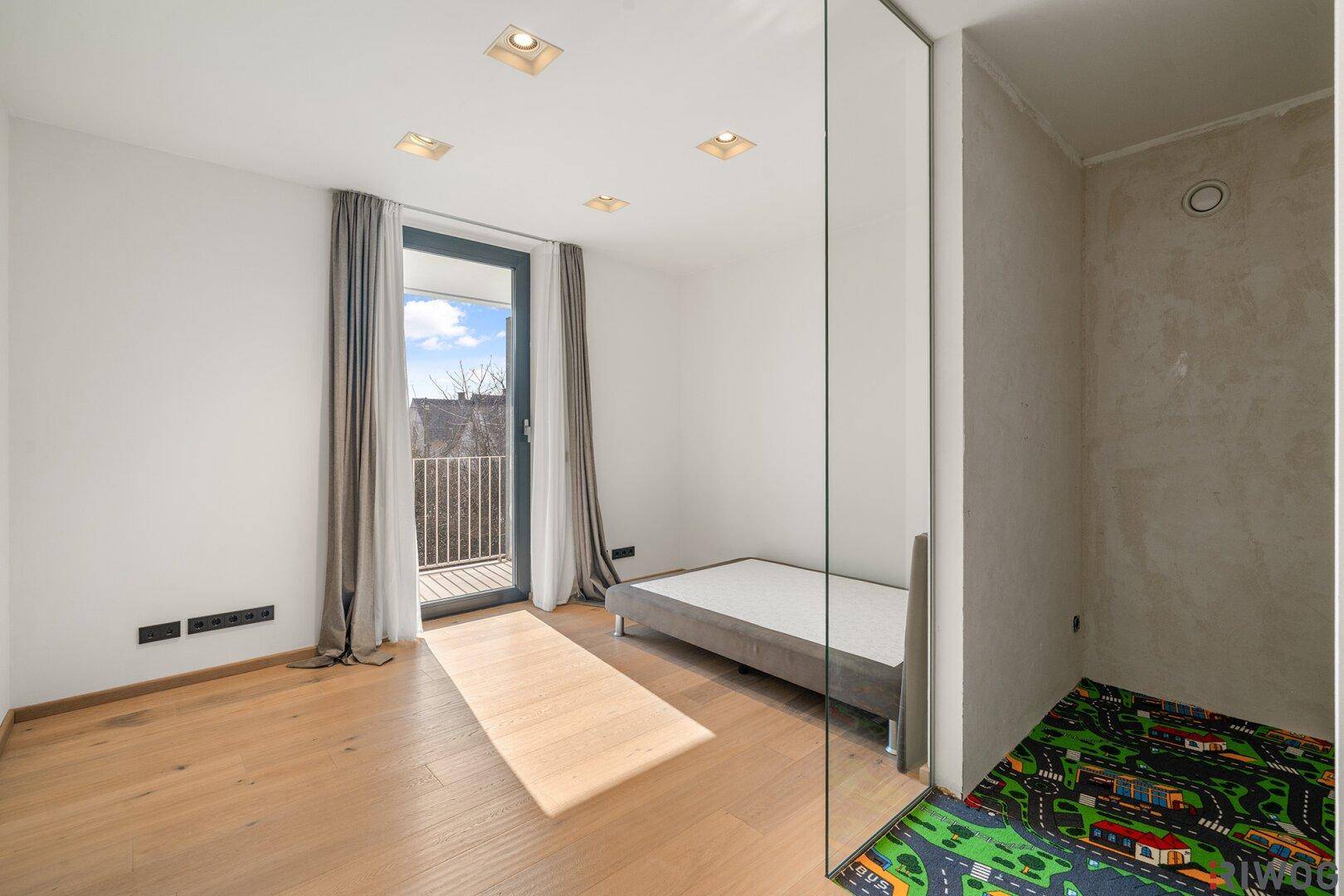 Freundliches Schlafzimmer mit Holzboden, französischem Balkon und viel Tageslicht.