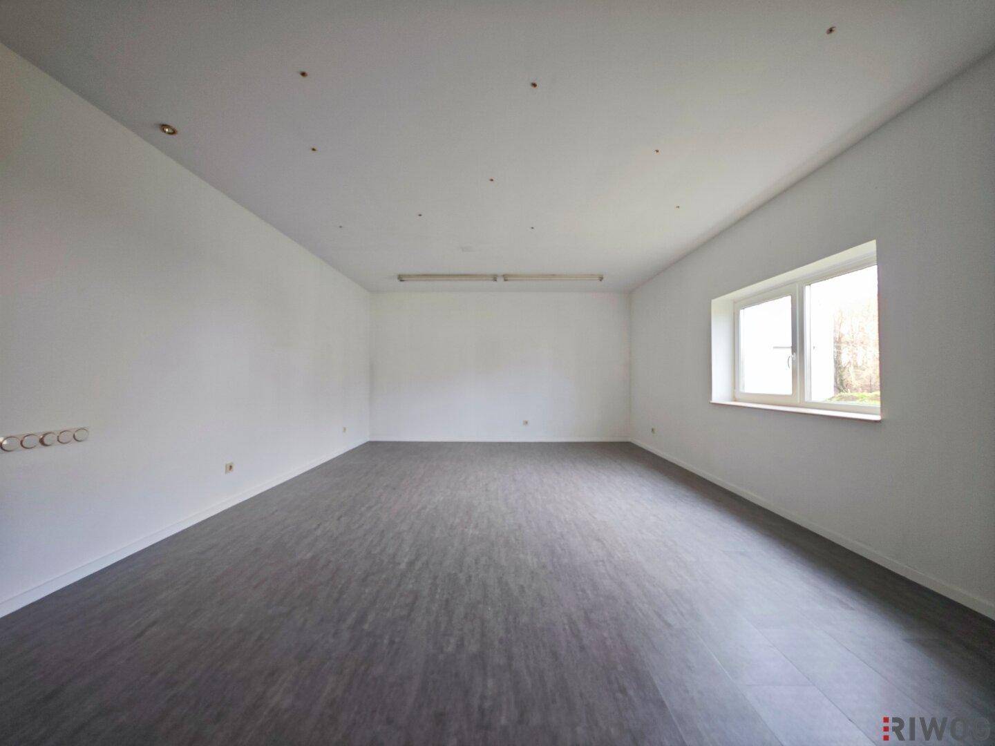 Geräumiger, heller Büroraum mit weiß gestrichenen Wänden und einem Fenster für Tageslicht.