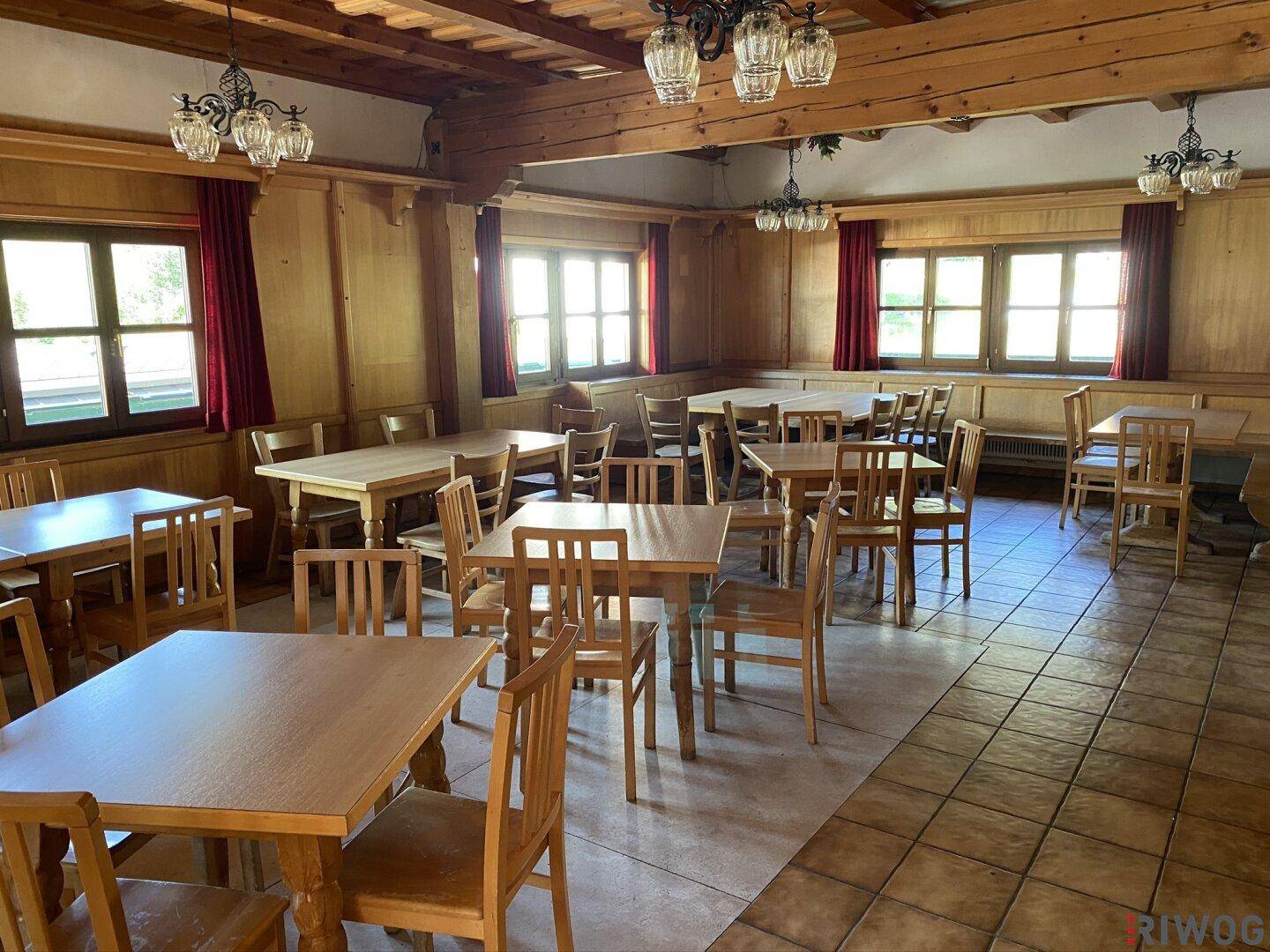 Heller Speisesaal mit vielen Holztischen und Stühlen, bereit für Gäste.