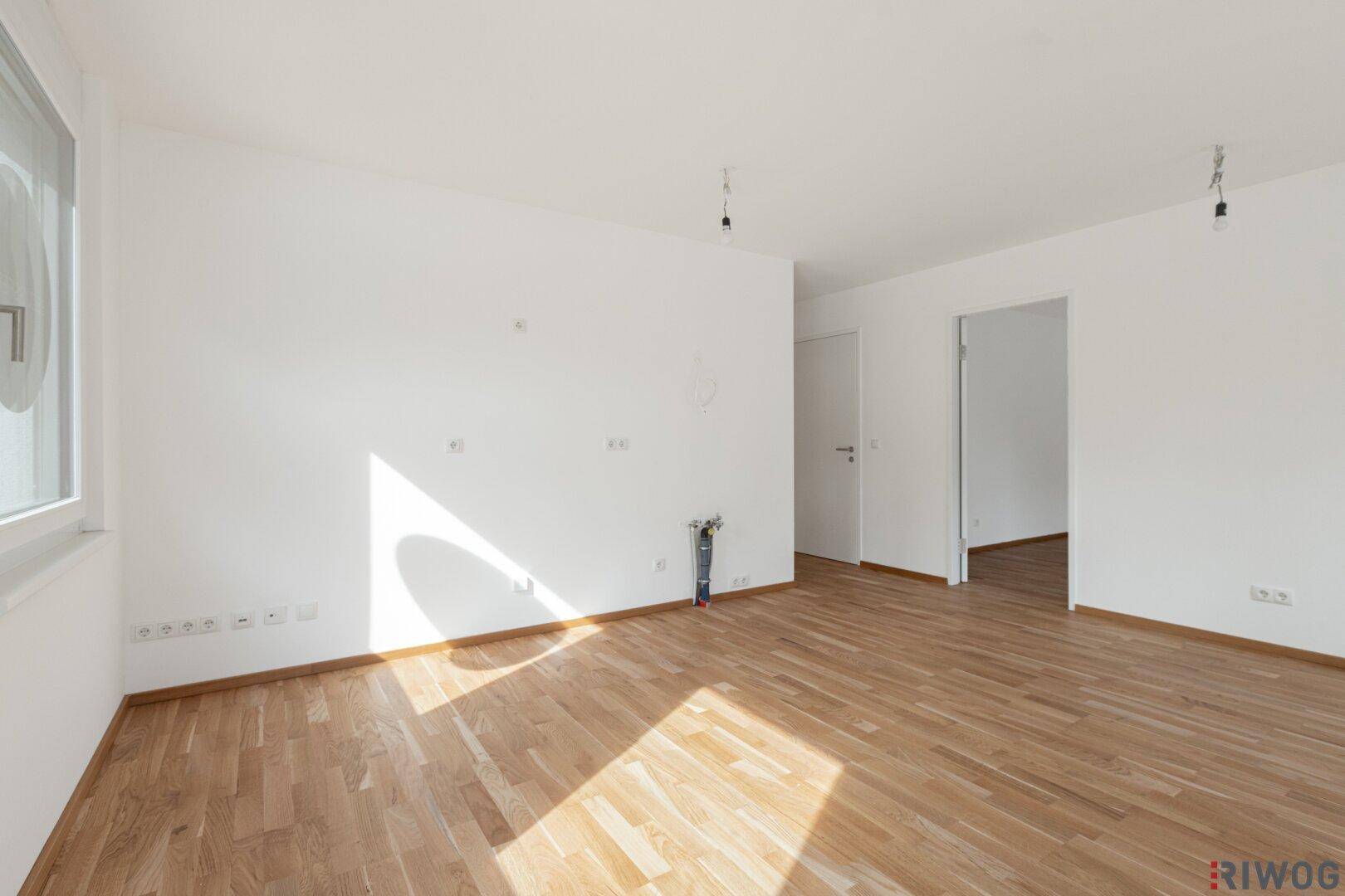 Geräumiger, heller Raum mit Holzboden und weißen Wänden, bereit zur individuellen Gestaltung.