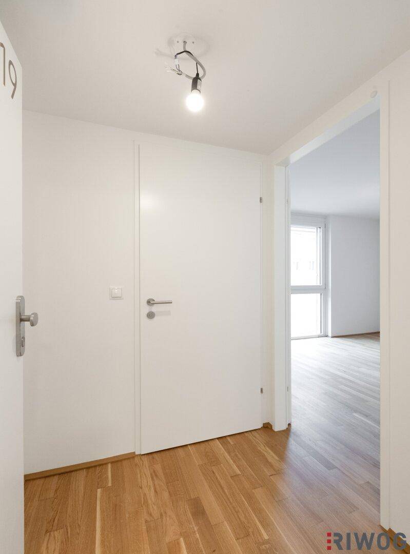 Heller Flur mit Holzboden und weißen Türen, führt zu den verschiedenen Räumen.