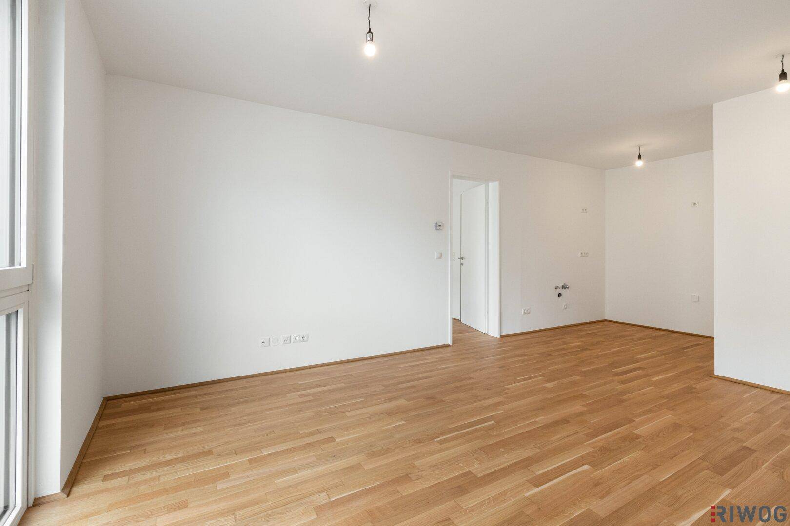 Heller, leerer Raum mit Holzboden und weißen Wänden, bereit zur individuellen Gestaltung.