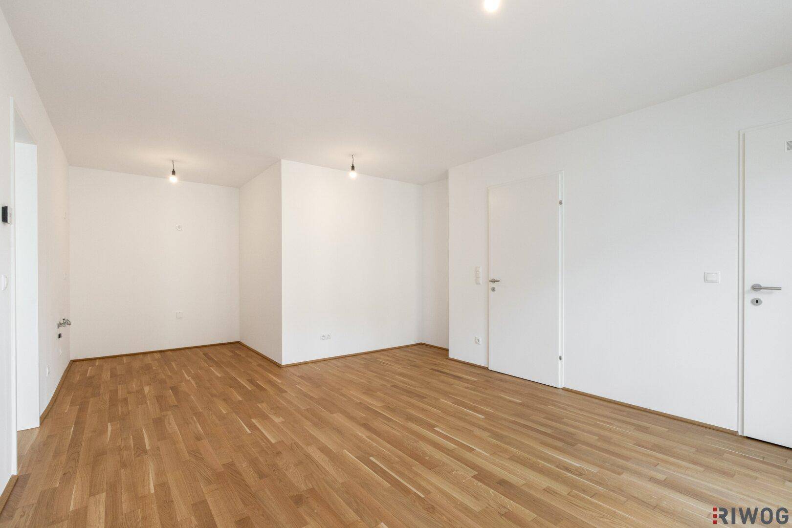 Leerer Raum mit Holzboden und mehreren weißen Türen, bietet vielseitige Nutzungsmöglichkeiten.