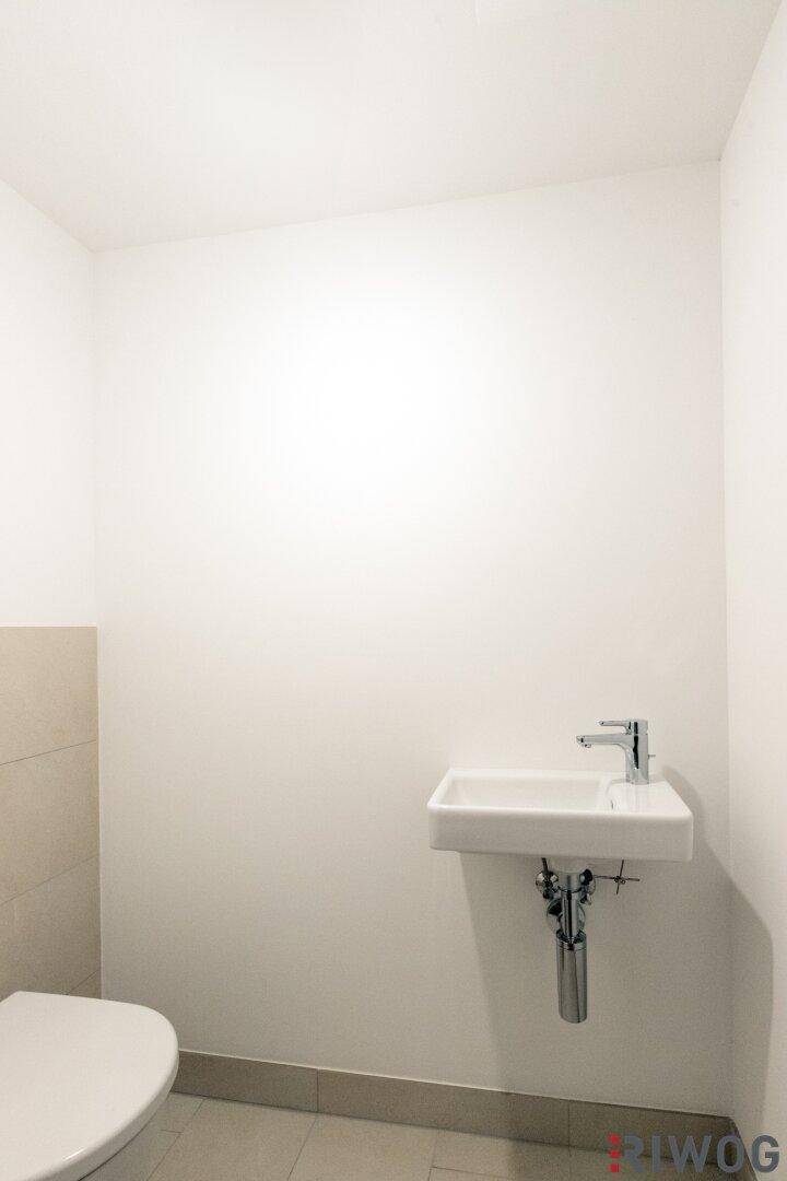 Gäste-WC mit modernem Wand-WC und kleinem Waschbecken, in schlichtem Design.