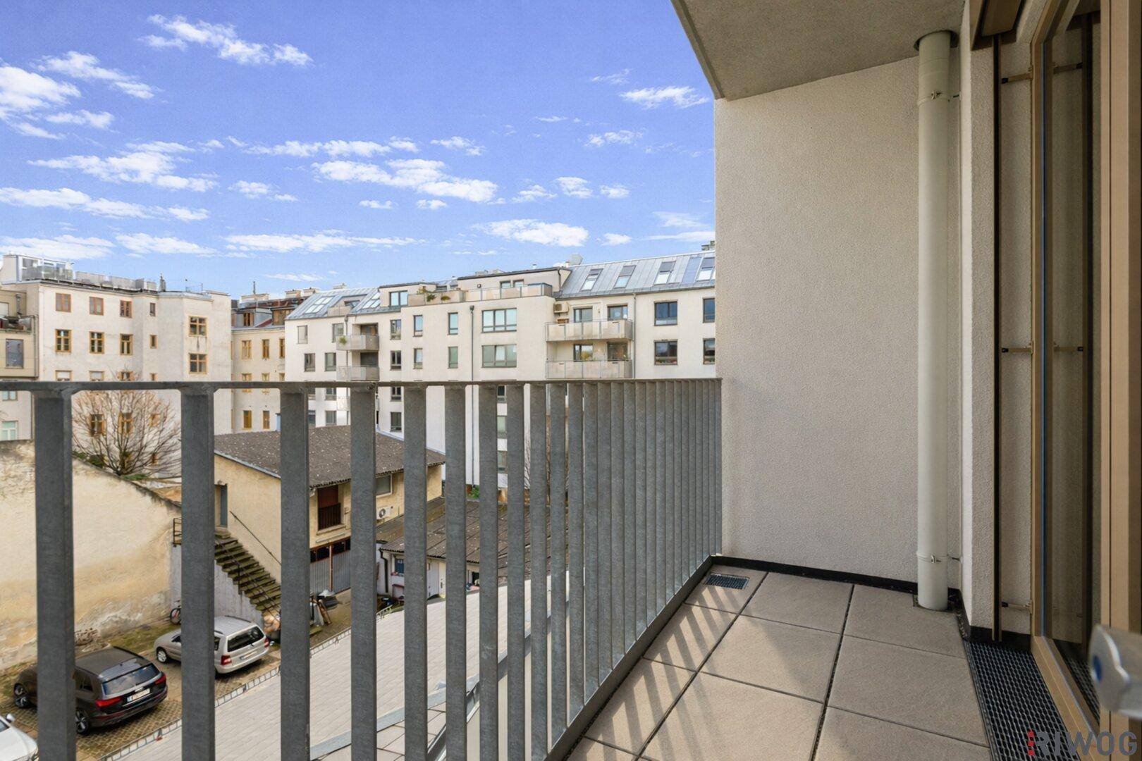 Heller Balkon mit Fliesenboden und Blick auf die umliegende Bebauung.