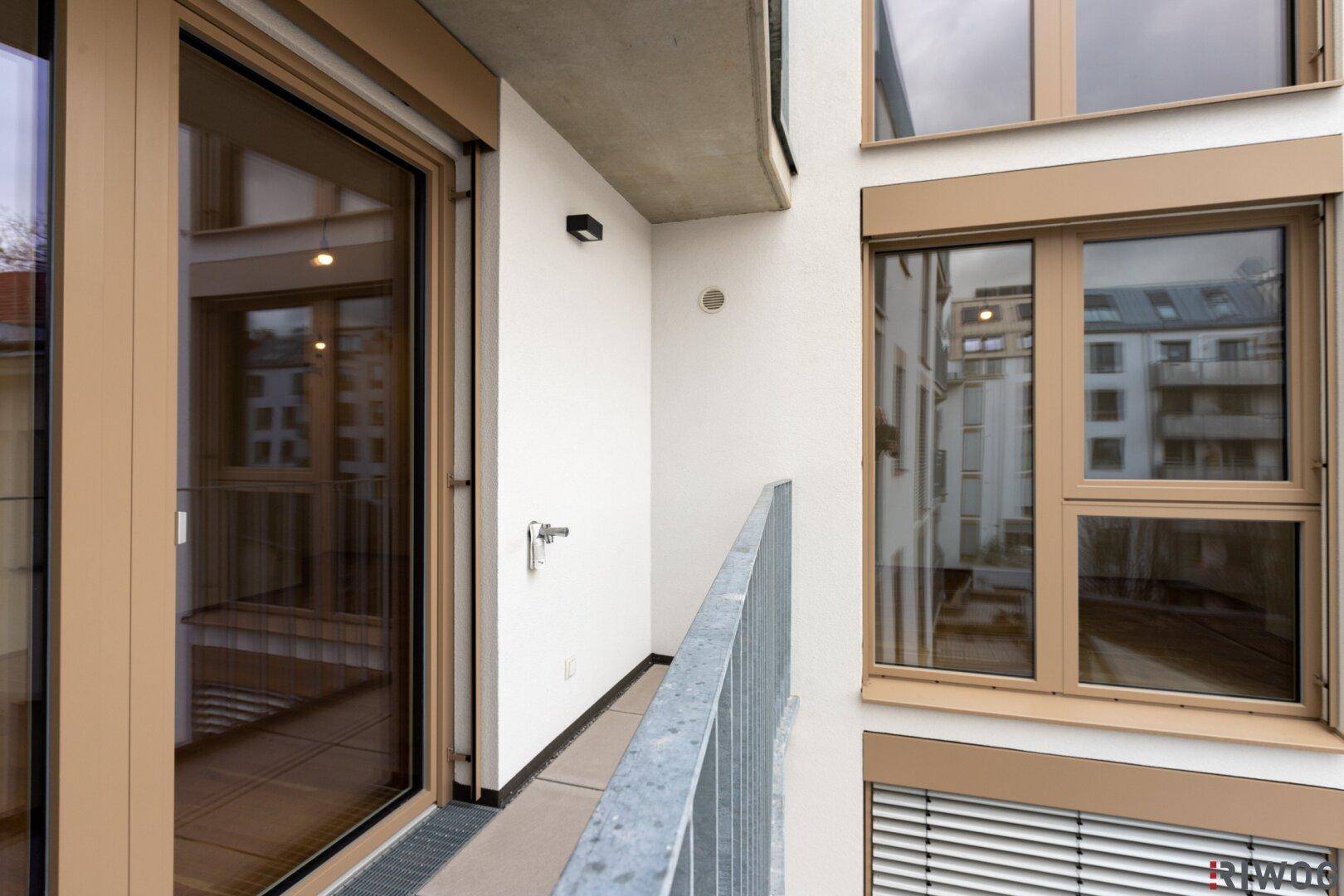 Balkon mit Fliesenboden und Blick auf die moderne Fassade des Gebäudes.