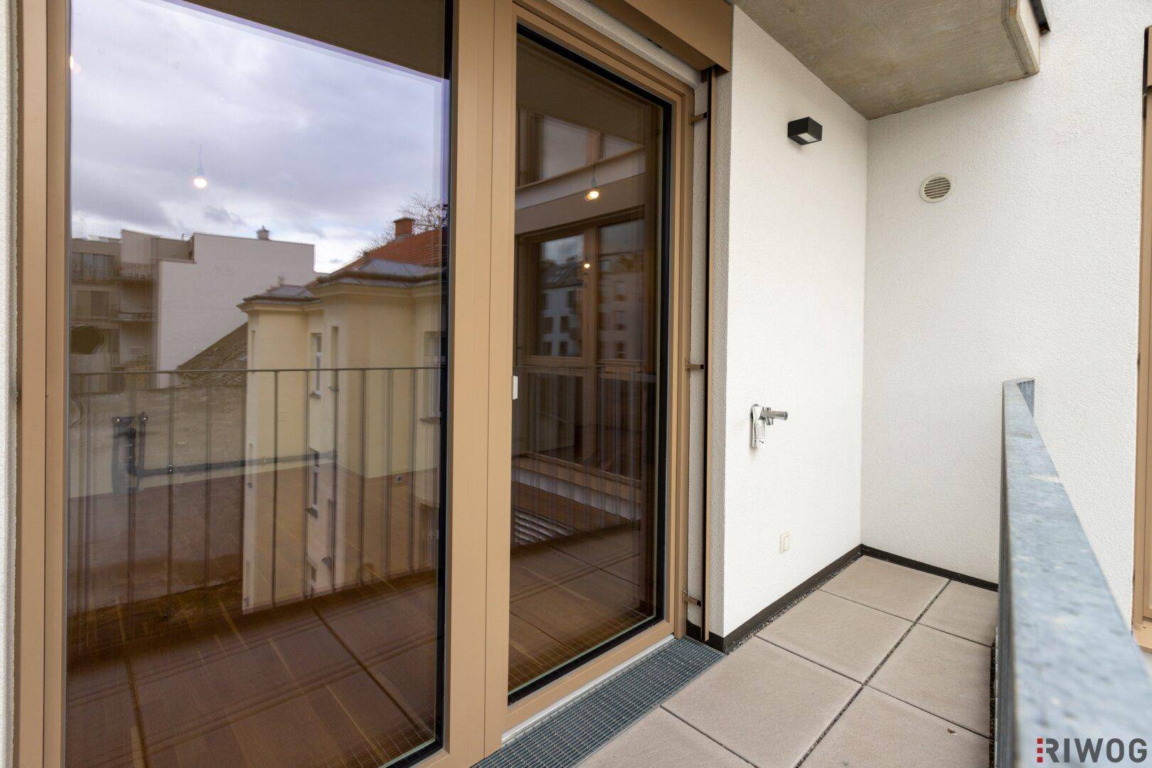 Heller Balkon mit Fliesenboden und Blick auf die umliegenden Gebäude.