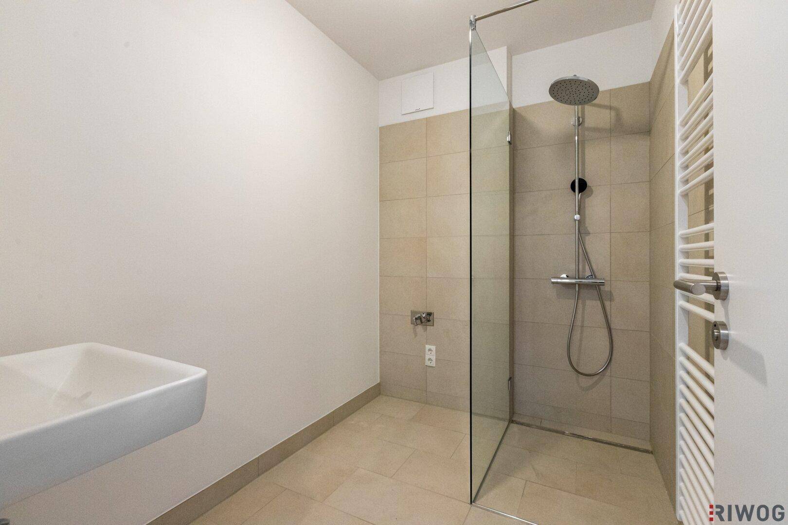 Modernes Badezimmer mit ebenerdiger Dusche, Fliesenboden und Handtuchheizkörper.