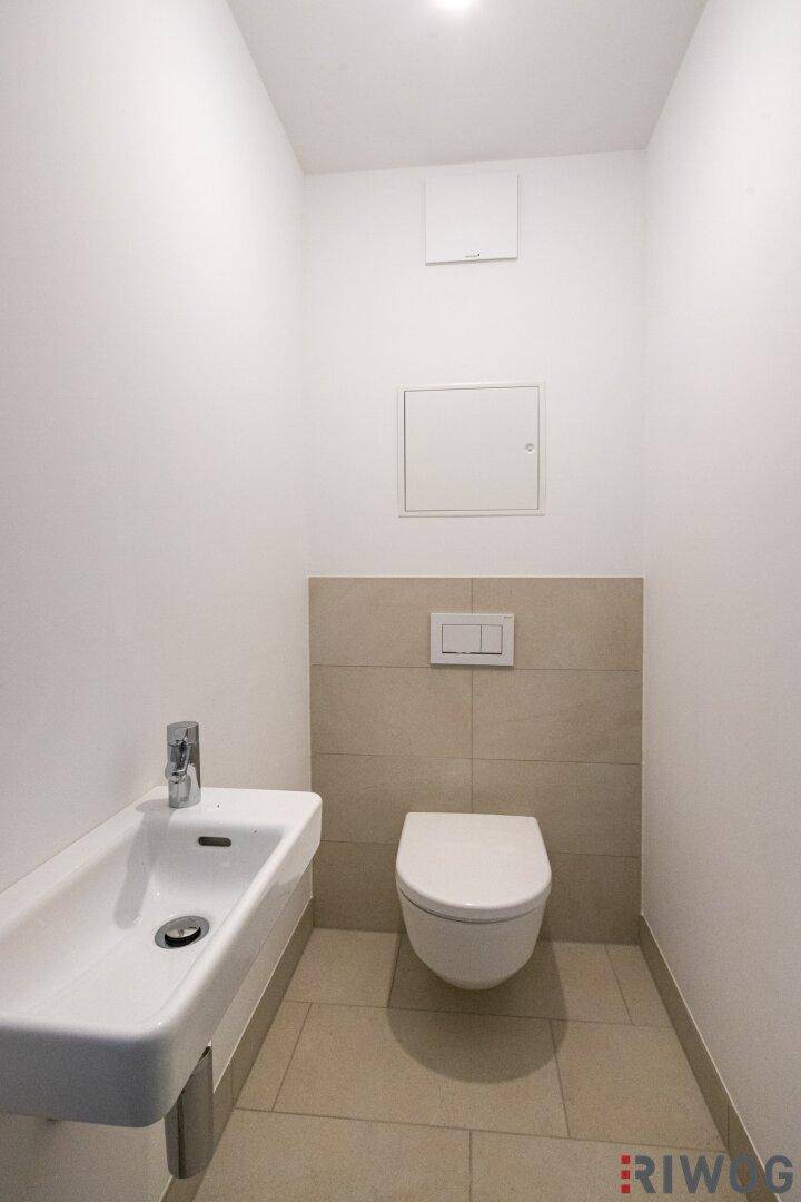 Kompaktes Gäste-WC mit wandhängendem WC und kleinem Waschbecken.